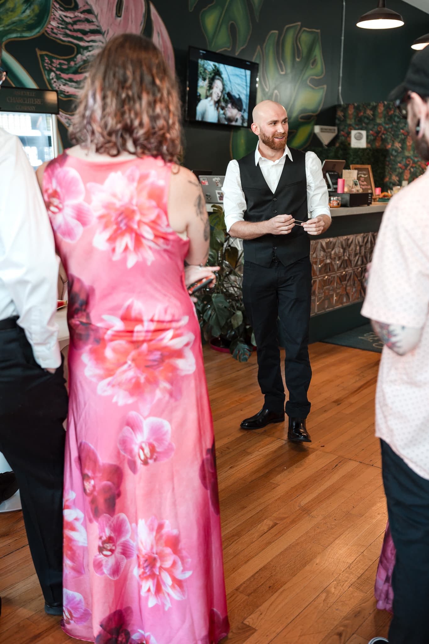 Dylan Looper performing close-up magic for guests at a wedding reception at Asheville Charcuterie Company